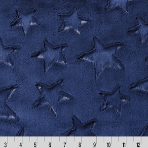 May include: Navy blue fabric with a star pattern. The stars are raised and have a fuzzy texture.