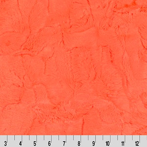 May include: A close-up of a bright orange fuzzy fabric. The fabric has a soft, plush texture.