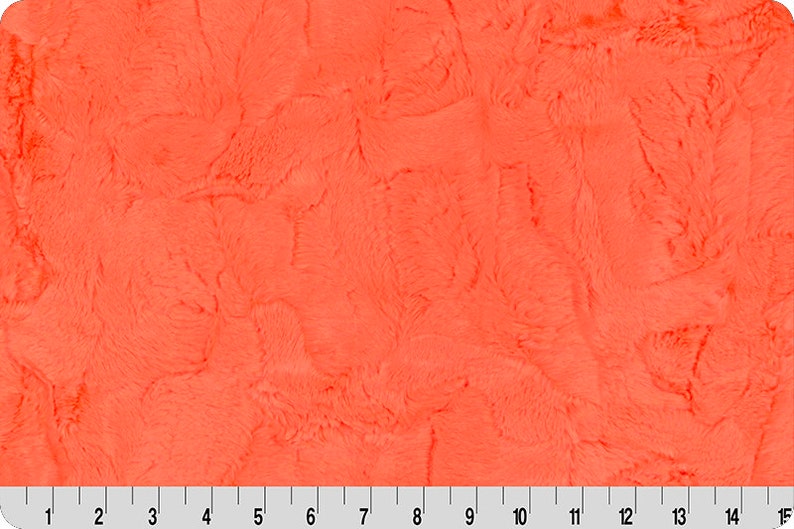 May include: A close-up of a bright orange fuzzy fabric. The fabric has a soft, plush texture.