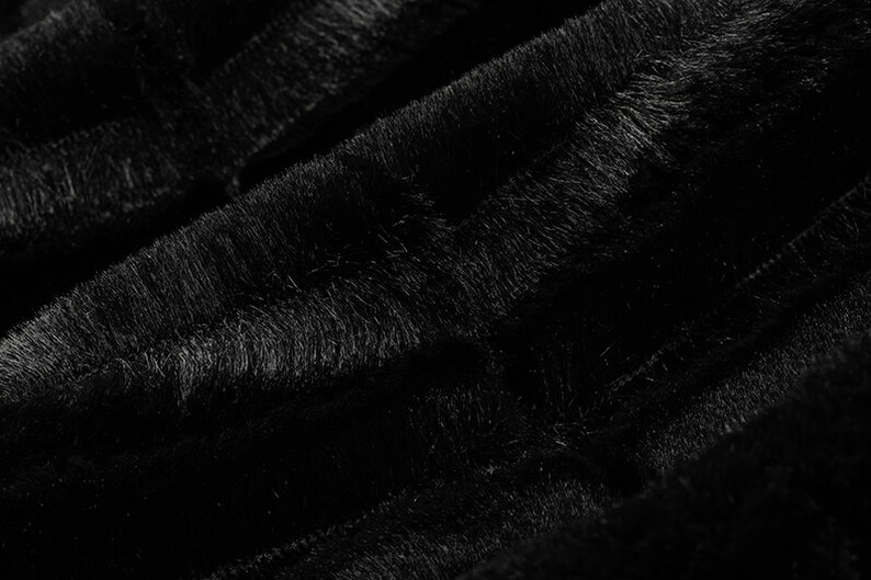 Pu&ograve; includere: Primo piano di un tessuto in peluche nero con una texture morbida e soffice. Il tessuto presenta un sottile motivo a righe.