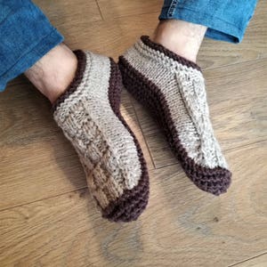 May include: A pair of knitted slipper socks with a brown and beige color scheme. The socks are made of a soft, warm material and have a comfortable fit.