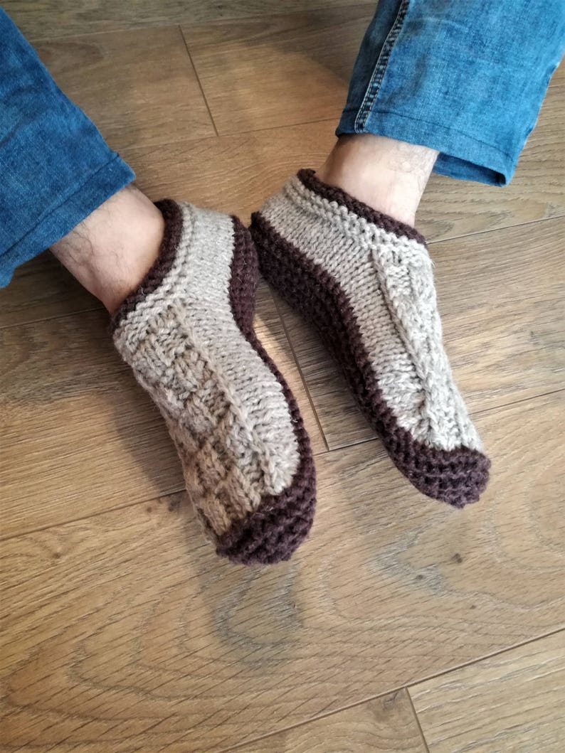 May include: A pair of knitted slipper socks with a brown and beige color scheme. The socks are made of a soft, warm material and have a comfortable fit.