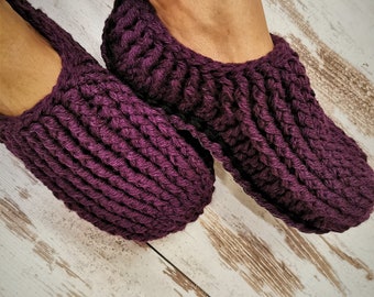 May include: A pair of purple crocheted slippers. The slippers are made with a thick yarn and have a simple design.