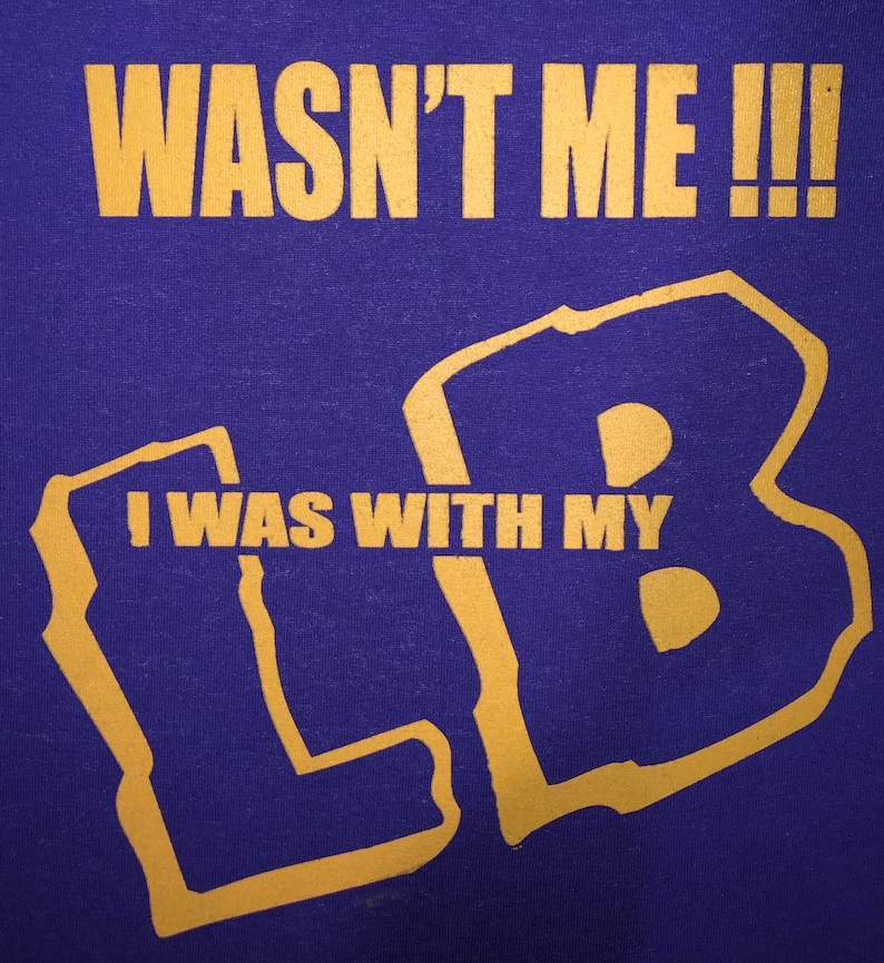 May include: Purple t-shirt with gold lettering that reads "Wasn't me!!! I was with my LB".