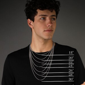 Op de afbeelding: Een persoon draagt een zwart t-shirt met een zilveren ketting. De kettinglengtes worden weergegeven op 45,7 cm, 50,8 cm, 55,9 cm, 61 cm, 66 cm, 71,1 cm en 76,2 cm. De merknaam "EIJI" staat op het shirt.