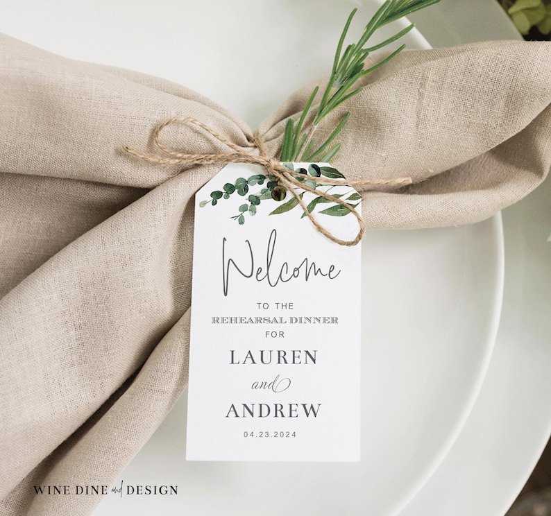 May include: White card with green foliage design. Text reads "Welcome to the Rehearsal Dinner for Lauren and Andrew 04.23.2024".
