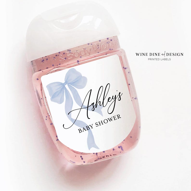 K&ouml;nnte beinhalten: Eine durchsichtige Plastikflasche mit einer blauen Schleife und dem Text "Ashley's Baby Shower" auf einem wei&szlig;en Etikett.