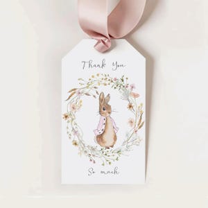 May include: A white thank you tag with a watercolor illustration of a brown rabbit wearing a pink jacket surrounded by a wreath of flowers. The text "Thank You So Much" is written in black cursive.