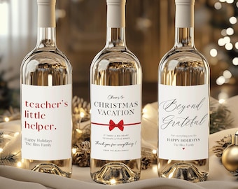 May include: Three clear glass wine bottles with white labels. The labels read "teacher's little helper", "Cheers to Christmas Vacation", and "Beyond Grateful". The bottles are on a white cloth with Christmas decorations in the background.