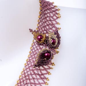 May include: A delicate beaded necklace with a geometric pattern and a floral design featuring purple and gold beads.