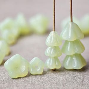 May include: A set of pale green glass beads in the shape of a flower. The beads are strung on a wire and are arranged in a cluster.