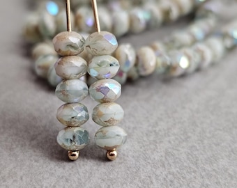 May include: Two strands of iridescent white glass beads with gold accents on a gold wire. The beads are faceted and have a subtle shimmer.