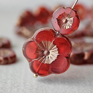 May include: Red glass flower beads with gold accents. The beads are strung on a wire and are ready to be used in jewelry making.