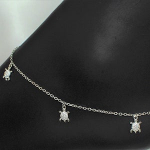 May include: A silver anklet with three dangling turtle charms. Each turtle charm is decorated with clear sparkling rhinestones.