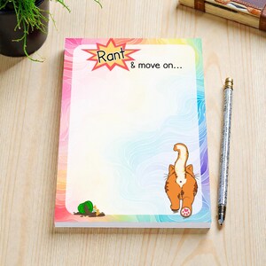 Pode incluir: Um bloco de notas com uma borda colorida de arco-íris e um design extravagante. O bloco de notas apresenta a parte traseira de um gato de desenho animado, um vaso derramado e o texto "Rant & move on..." em uma estrela.