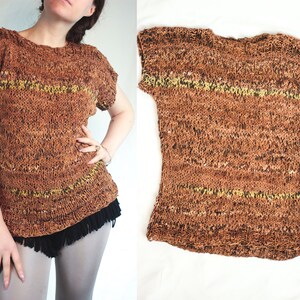 Könnte beinhalten: Ein brauner Strickpullover mit kurzen Ärmeln und einem gelben Streifen-Detail. Der Pullover hat einen Fransen-Saum.