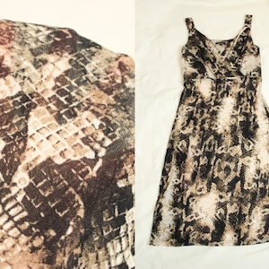 Op de afbeelding: Een maxi-jurk zonder mouwen met een slangenhuidprint in bruine en beige tinten. De jurk heeft een V-hals en een wikkel-bovenstuk.