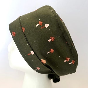 May include: A green scrub hat with a mushroom print. The hat has a tie at the back.