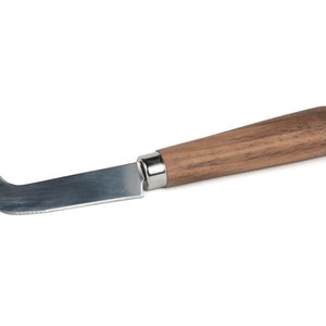 Puede incluir: Un cuchillo de queso de acero inoxidable con mango de madera. El cuchillo tiene una hoja curva y una punta puntiaguda.