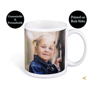May include: White ceramic mug featuring a photograph of a young girl with blonde hair and blue eyes, wearing a denim jacket. The mug has a handle and is printed on both sides.