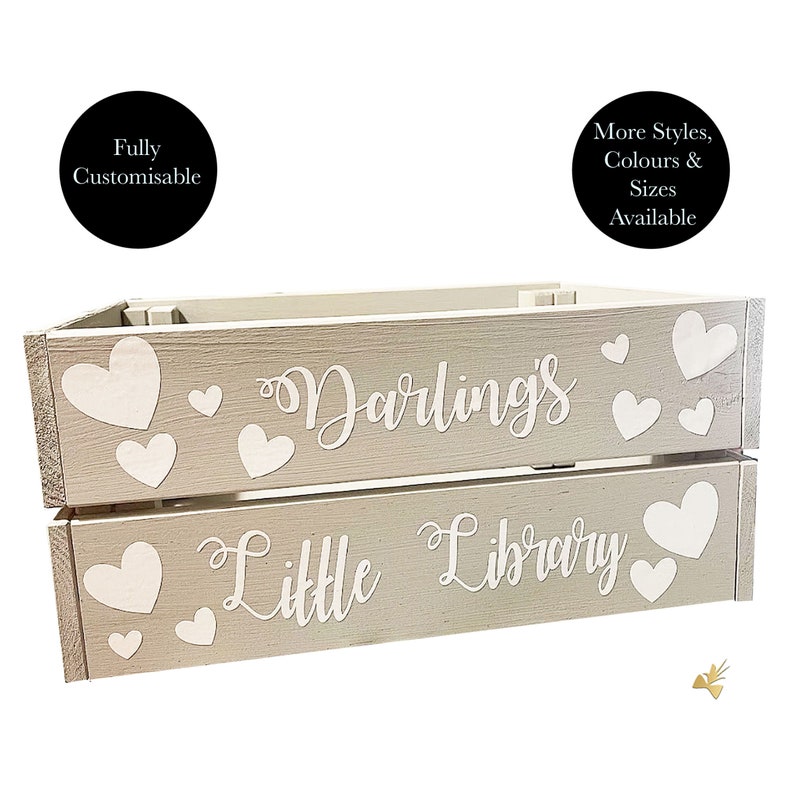 May include: A two-tiered, light gray wooden crate with white heart accents. The top tier reads "Darling's" and the bottom tier reads "Little Library" in cursive. The crate is designed for storage and organization.