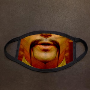 May include: A black face mask with a printed image of a man's face with a mustache and goatee. The man's mouth is open and his eyes are closed.