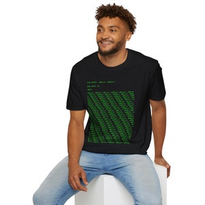 May include: Black t-shirt with green text. The text includes the phrase "HELLO, WORLD!" repeated multiple times in a grid-like pattern. The shirt is a classic crew neck style.