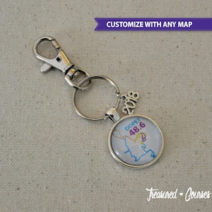 May include: A silver keychain with a round charm featuring a map of the Dopey 48.6 course. The charm also includes the year 2018. The keychain is attached to a silver split ring.