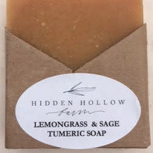 May include: A bar of handmade soap wrapped in brown paper with a white label that reads "HIDDEN HOLLOW FARM LEMONGRASS & SAGE TUMERIC SOAP".