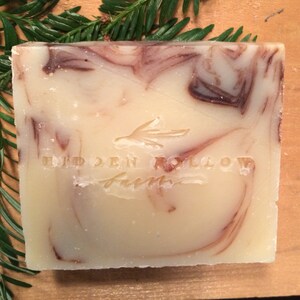 May include: A bar of white soap with brown swirls and the text "HIDDEN HOLLOW FARM" embossed on the front.