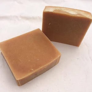 May include: Two bars of handmade soap, both are a light brown colour.