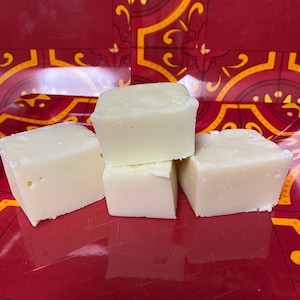 May include: Four white fudge squares on a red and yellow patterned surface.