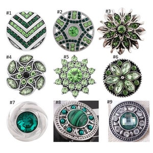 May include: Nine different green and silver snap jewelry buttons. The buttons feature various designs including geometric patterns, flowers, and a green stone.