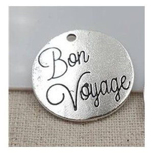 May include: Silver charm with the text "Bon Voyage" in black lettering.