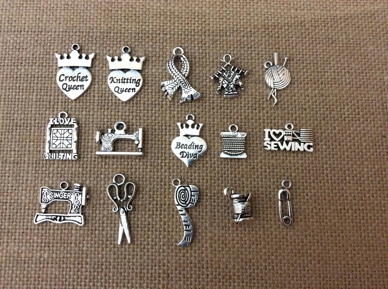 Puede incluir: Una colecci&oacute;n de 15 colgantes de plata con varios dise&ntilde;os de tem&aacute;tica artesanal, incluyendo "Crochet Queen", "Knitting Queen", "Beading Diva", "I Love Sewing" y "Quilting".