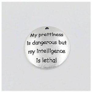 May include: A round, silver-colored charm with a hole at the top. The charm features the engraved text: "My prettiness is dangerous but my intelligence is lethal."