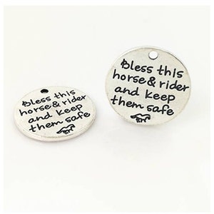 Puede incluir: Dos dijes redondos de plata con el texto "Bless this horse & rider and keep them safe" en cada dije.
