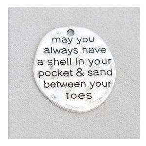 May include: Silver charm with the text "may you always have a shell in your pocket & sand between your toes".