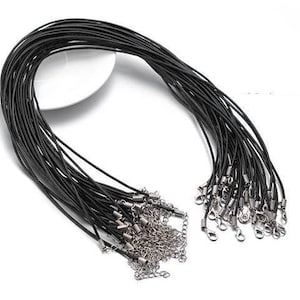 May include: A bundle of black leather cords with silver clasps. The cords are arranged in a circle and are ready to be used for jewelry making.