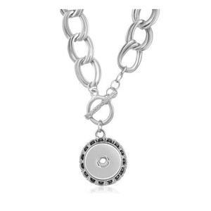 Puede incluir: Collar de cadena de plata con un gran dije redondo de plata con borde negro. El dije tiene un pequeño botón redondo de plata en el centro.
