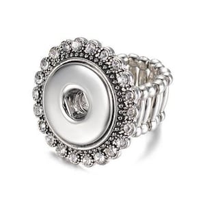 May include: A silver adjustable ring with a round, clear crystal-encrusted bezel that holds a 18mm snap-in button.