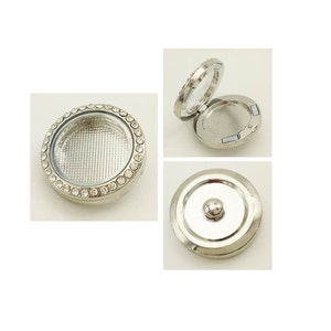 May include: Silver locket with a clear glass insert and a circle of rhinestones around the edge. The locket is open to show the inside, which is also silver.