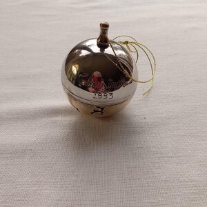 May include: Silver and gold Christmas ornament with the words "Christmas 1993" engraved on it.