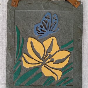 May include: A slate wall hanging with a yellow flower and a blue butterfly. The flower and butterfly are cut out of the slate and painted.