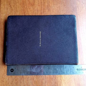 May include: A rectangular, dark purple, textured book cover with the name R. Geneva Alexander embossed in gold lettering. A metal Westcott ruler is positioned along the bottom edge, showing the book is approximately 9 inches in length.