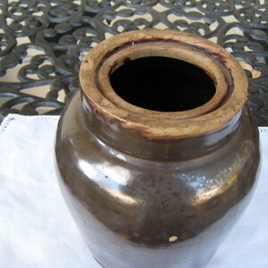 May include: A brown glazed stoneware crock with a wide opening and a lid. The crock has a rustic, vintage look and is perfect for storing food or other items.
