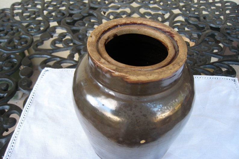 May include: A brown glazed stoneware crock with a wide opening and a lid. The crock has a rustic, vintage look and is perfect for storing food or other items.