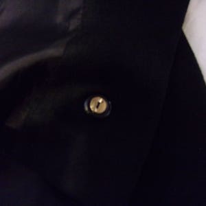 May include: A black jacket with a single gold button.