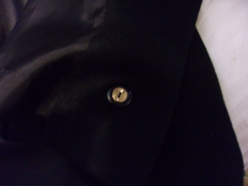 May include: A black jacket with a single gold button.