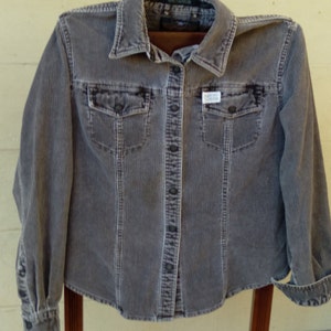 May include: A gray corduroy button-up shirt with long sleeves and a small "Harley Davidson" logo patch on the front.